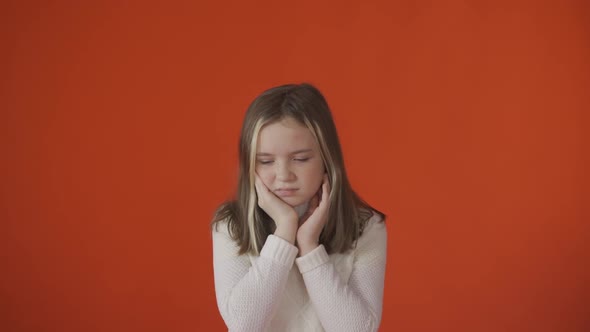 A Little Girl Hurts Her Tooth Against a Orange Background