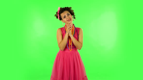 Lovely Girl Looks with Tenderness with Folded Arms in Front of Her. Green Screen