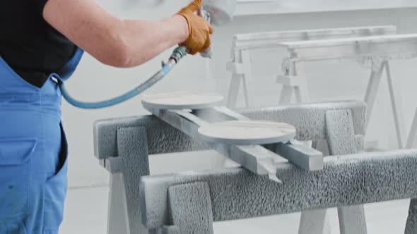 Man Worker Covering a Wooden Piece with White Paint