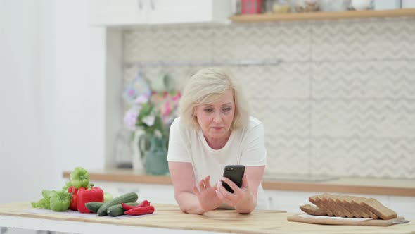 Old Woman Using Smartphone in Kitchen