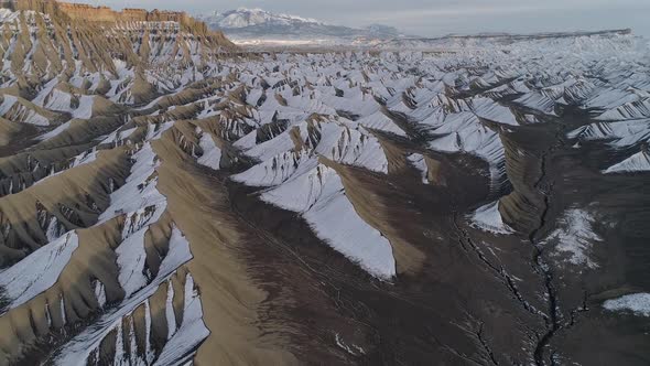 Flying backwards away from snow covered dunes in the Utah desert