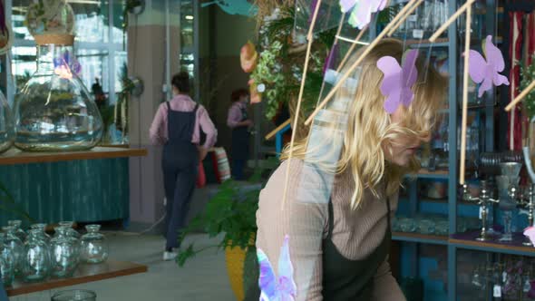 A Beautiful Woman with White Hair Chooses Houseplants in a Glass Vase in a Greenhouse Among the