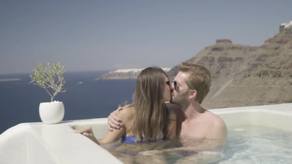 Couple Kissing in Hot Tub on Terrace Overlooking the Ocean