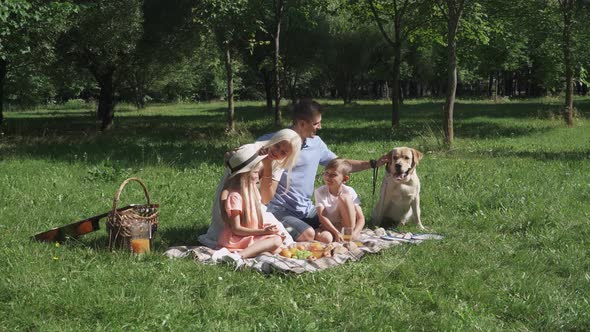 Picnic in Nature, Parents and Children Sit on a Blanket and Communicate, Family with Dog Relax in a