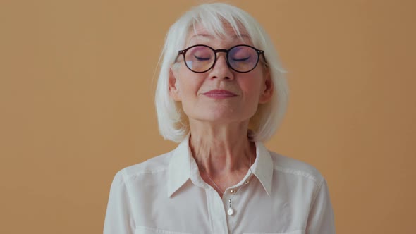 Handsome mature woman looking around and showing silence gesture