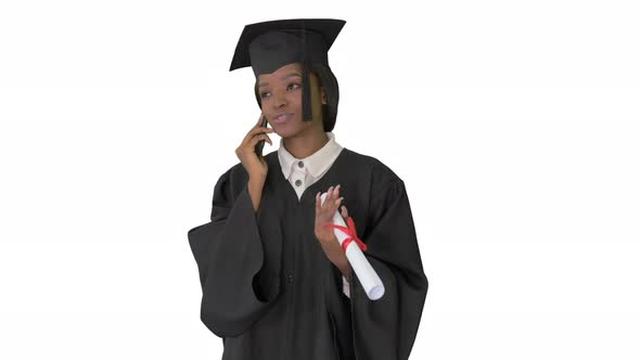 African American Female Student in Graduation Robe Talking on the Phone on White Background