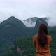 A female traveler taking a photo of a beautiful greenery mountains on foggy day - VideoHive Item for Sale