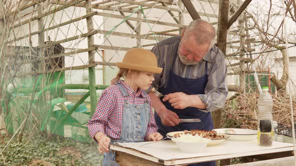 Grandfather and Granddaughter Taste Grilled Meat Kebab From the Grill Grate