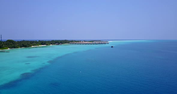 Wide fly over travel shot of a white sand paradise beach and blue ocean background in high resolutio