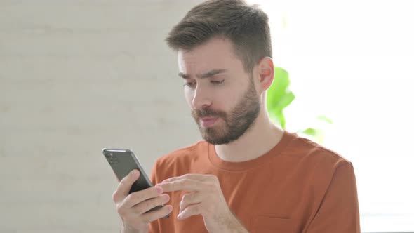 Young Man Reacting to Loss on Smartphone