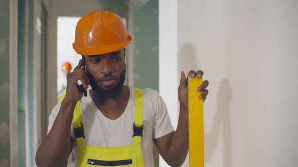 African Construction Worker on Building Site Talking on Mobile Phone