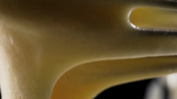 Beaten Eggs Flowing Down the Whisk on a Black Background