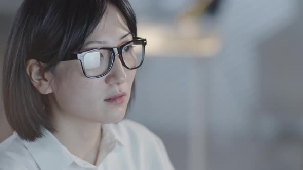 Focused Woman Working on Computer in Dark Office