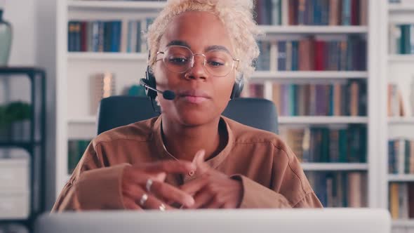 Young African American Business Woman Looks in Laptop and Using Wired Headset