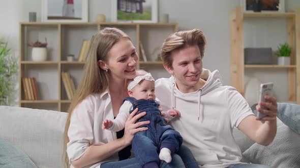 Young Family Taking a Selfie on the Sofa in the Living Room