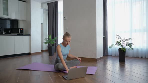 Sporty Woman Training at Home and Using Laptop