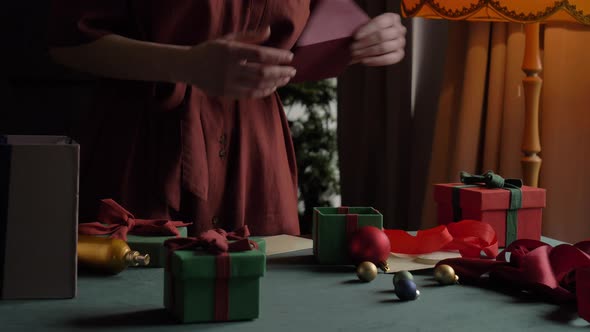 woman preparing gifts for christmas at home on the table