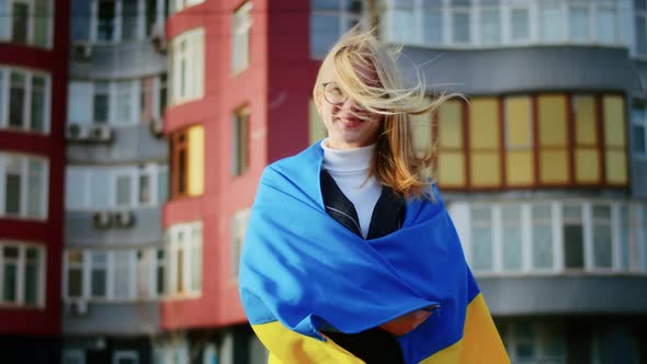 Portrait of a Joyful Ukrainian Woman Holding a Ukrainian Flag and a Sign