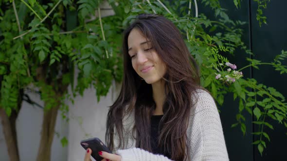 Slow motion shot of smiling woman using smartphone