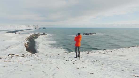 Young Woman Tourist Takes Pictures at the Top of the Cliff Around Reynisfjara Beach and Dyrholaey