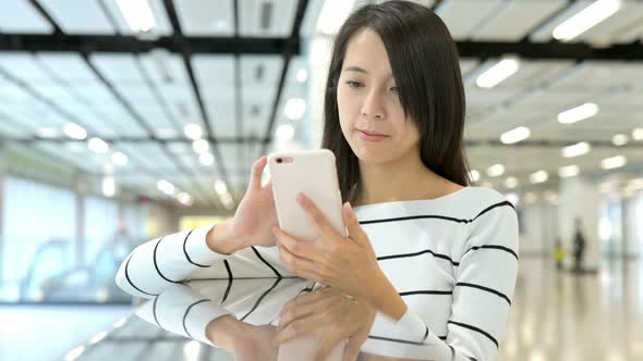 Woman reading cellphone in station hall 