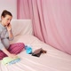 Happy pregnant woman calling on smartphone while sitting on bed in bedroom - VideoHive Item for Sale