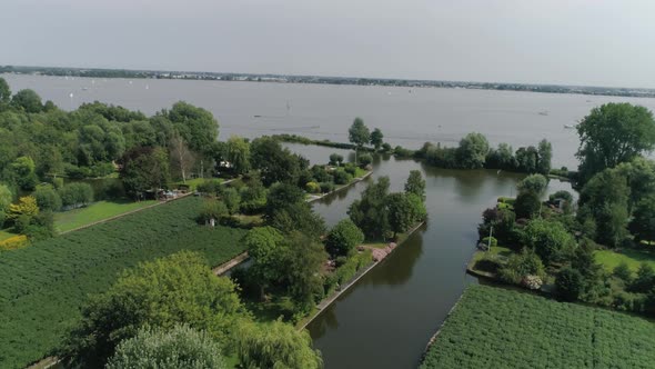 Aerial Slomo shot of Green Dutch Countryside with Small Boats, Streams and Lake, during Sunny Weathe