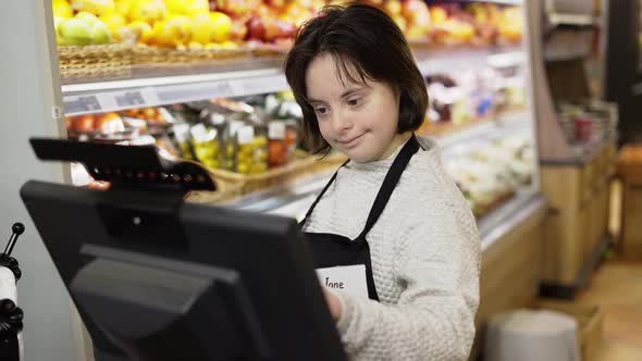 Worker with Down Syndrome Using a Digital Tablet in the Fresh Produce Section of a Grocery Store