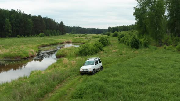 Aerial View of a Car Driving in Nature Near the River