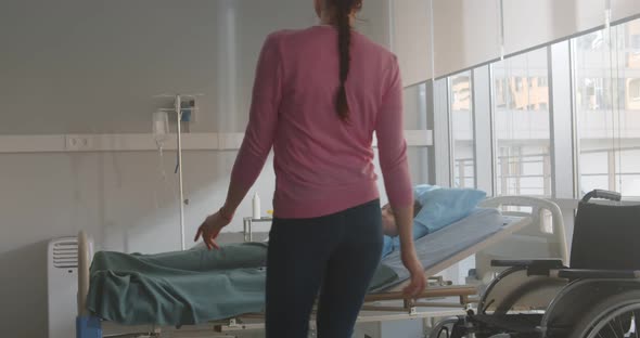 Mother Visiting Son Lying in Bed in Hospital Ward