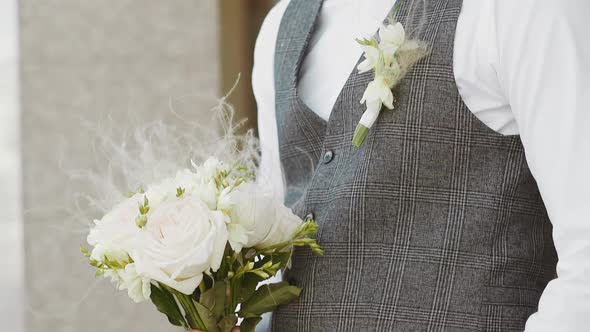 Elegant Young Man in Grey Vest with Boutonniere and Flowers