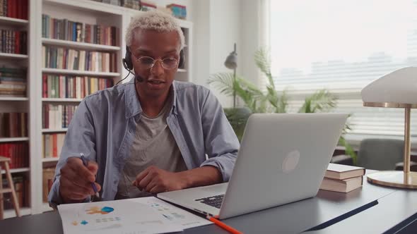 African Man Working with Laptop and Using Headset While Having Online Meeting