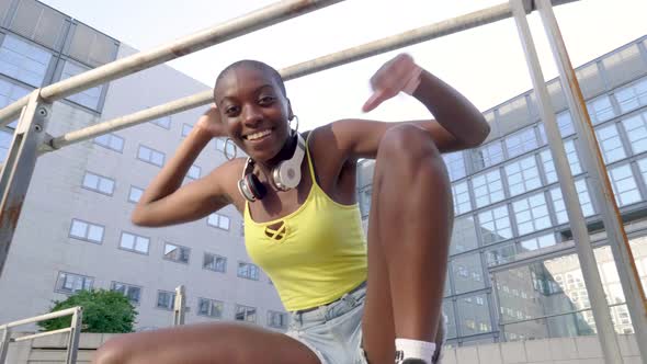 Young woman with headphones gesturing at railing