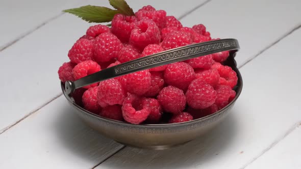Ripe Raspberries in Vintage Metal Bowl Rotation on a White Wooden Table