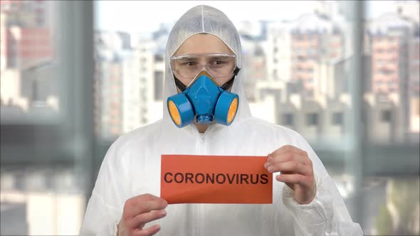 Portait Od Man in Protective Clothing and Respiratory Mask Holding Paper with Coronavirus Word