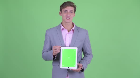 Happy Young Businessman Talking While Showing Digital Tablet