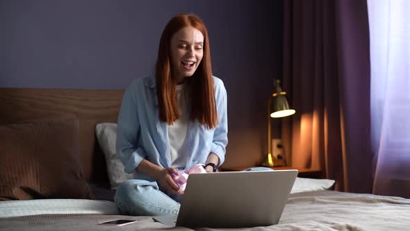 Pretty Happy Young Woman Thanks for Gift During Online Communication Using Laptop Computer.