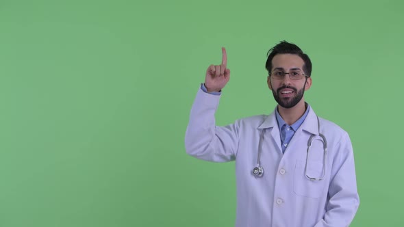 Happy Young Bearded Persian Man Doctor Talking and Pointing Up