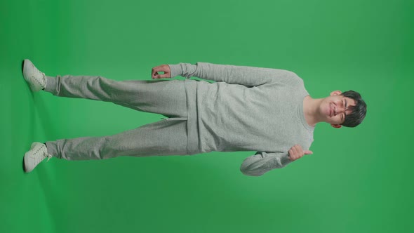 Full Body Of Asian Man Showing Thumbs Up Gesture And Smiling On Green Screen Studio