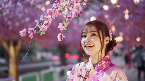 woman in yukata (kimono dress) looking sakura flower or cherry blossom blooming in the garden