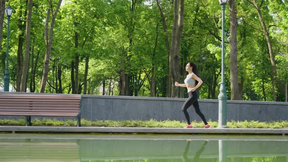 Fit Woman Jogging Along Pond in Park