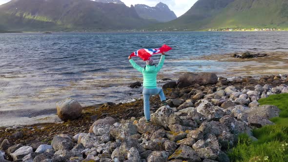 Woman with a Waving Flag of Norway on the Background of Nature