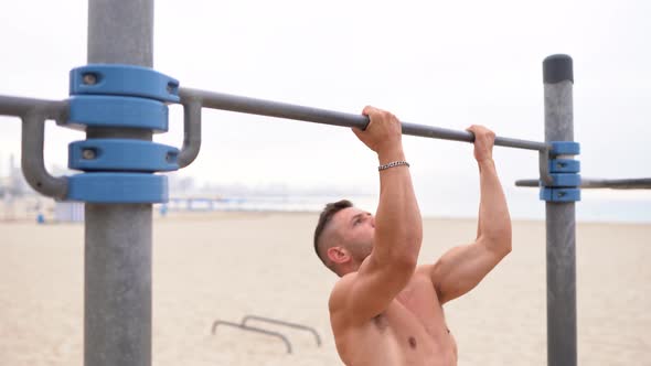 Fit sportsman doing pull ups on bar