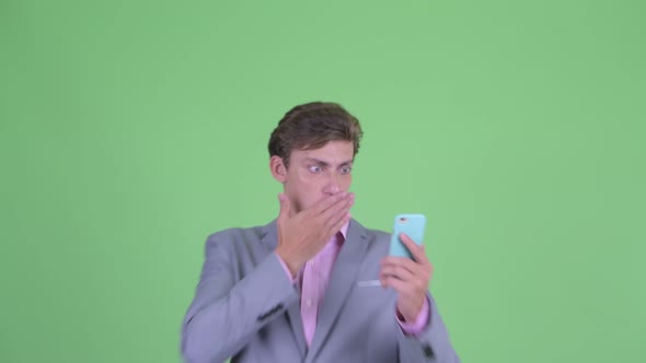 Face of Young Businessman Using Phone and Looking Shocked