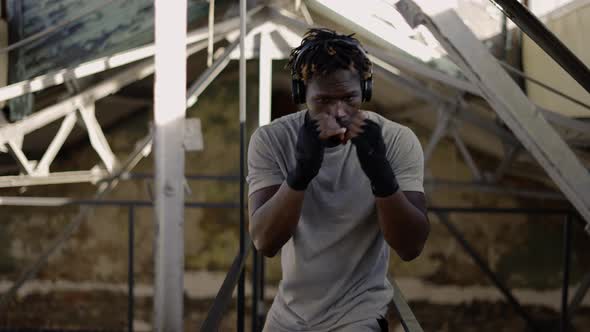 Afro American Young Male Boxer Practicing Shadow Boxing Around the Metal Structures