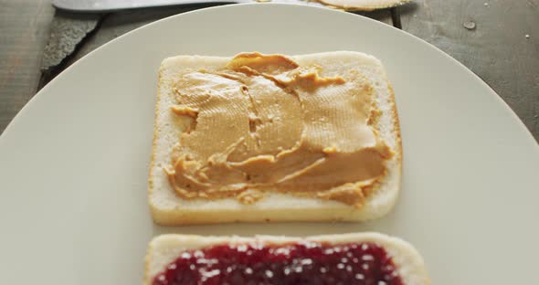 Close up view of peanut butter and jelly sandwich in a plate on wooden surface