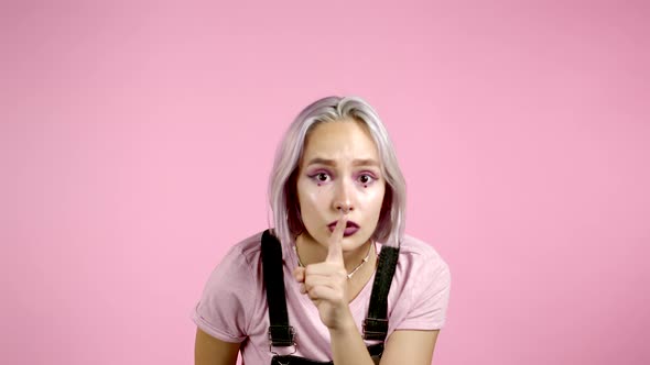 Girl with Violet Hairstyle Holding Finger on Her Lips Over Pink Background. Gesture of Shhh, Secret