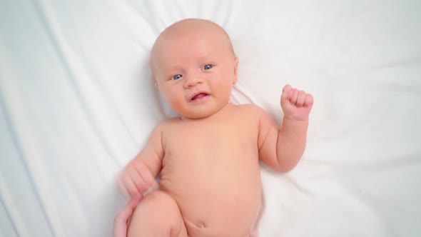 Hands Do Exercises to Baby on White Sheet