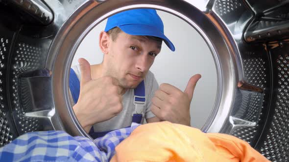 Washing machine repair worker looks inside mababan and shows class.