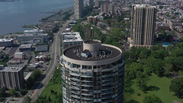 A drone view of a tall cylindrical building on the New Jersey side of the Hudson River on a sunny da